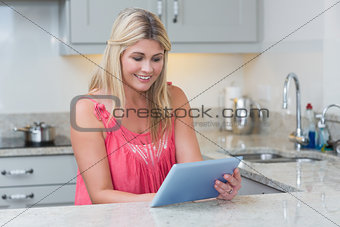 Casual woman using digital tablet in the kitchen