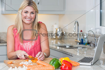 Portrait of woman making recipe from internet on laptop in kitchen
