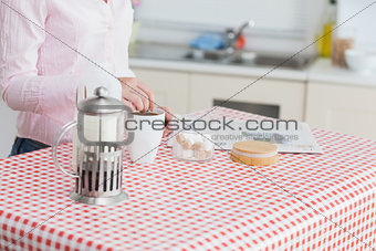 Woman with kettle and coffee cup