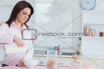 Young woman pouring milk in bowl