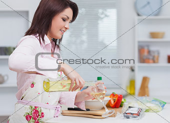 Young woman pouring wine while cooking food