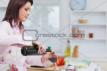 Young woman pouring wine while preparing food