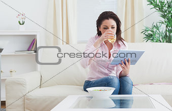 Woman drinking wine while using digital tablet at home