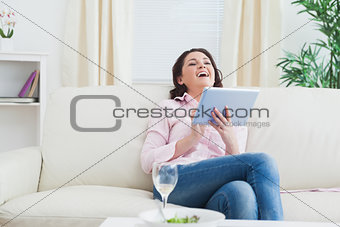 Casual cheerful woman using digital tablet on sofa
