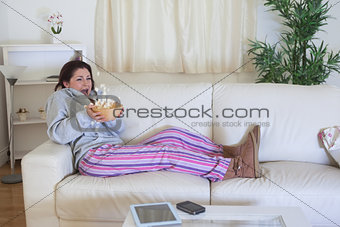 Scared woman throwing popcorn while watching film on couch