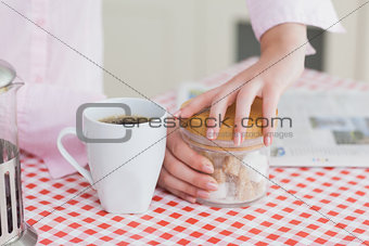 Woman with coffee cup and container of sugar cubes