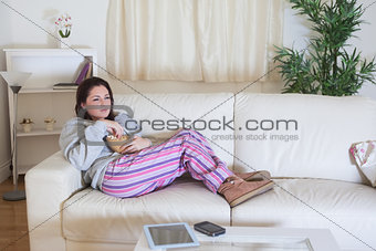 Relaxed woman with popcorn bowl watching tv