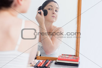Young woman applying makeup on face