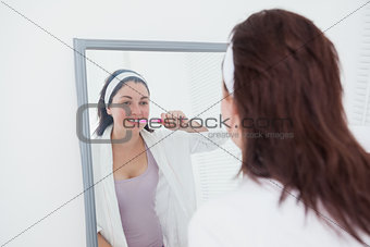 Woman brushing teeth in mirror