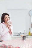 Thoughtful woman drinking coffee in the kitchen
