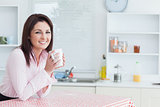 Happy woman with coffee cup in the kitchen