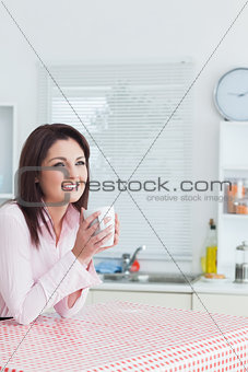 Happy woman looks away with coffee cup in hands