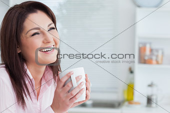 Cheerful woman looking away while drinking coffee