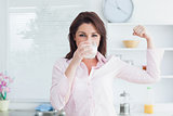 Woman drinking milk and flexing muscles
