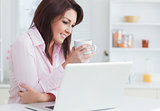 Smiling woman with coffee cup using laptop