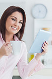 Smiling woman with coffee cup and digital tablet