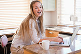 Cheerful young woman using laptop in kitchen