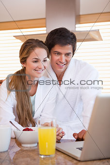 Couple using laptop over breakfast