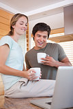 Couple using laptop while drinking coffee