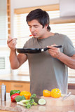 Young man smelling food in the kitchen