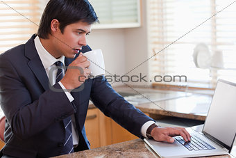 Business man using laptop while drinking coffee