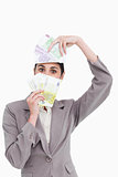 Business woman holding fanned banknotes over face