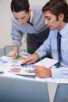 Colleagues looking at business graphs at office