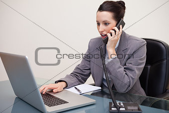 Shocked business woman using laptop while on call