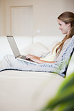 Casual woman sitting on sofa and using laptop