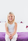 Little girl sitting on a double bed