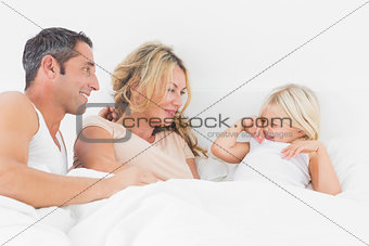 Parents looking her daughter on a bed