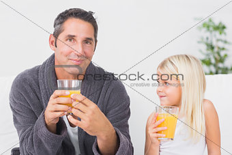 Father and daughter drinking glass of orange juice