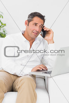 Busy man using his laptop and his phone