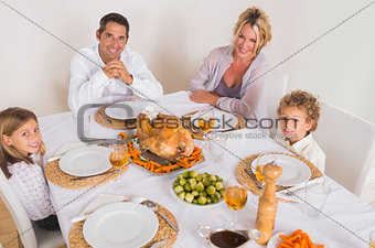 Family smiling around a roast dinner