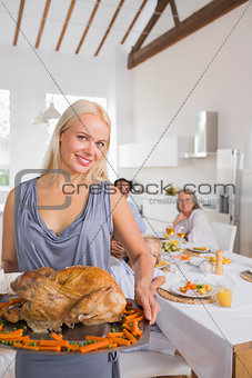 Smiling blonde woman showing the roast turkey