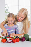 Focused mother teaching cutting vegetables