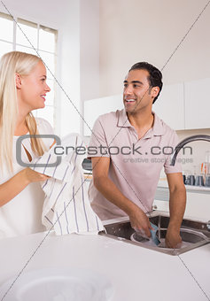 Talking couple washing dishes together