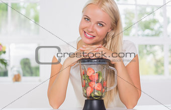 Smiling woman putting hands on the mixer