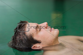 Handsome man floating in the pool