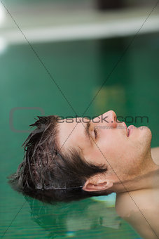 Relaxed man floating in pool