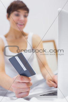 Smiling woman shopping online on bed