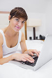 Pretty woman using laptop on bed