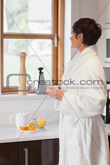 Woman looking out of window with a coffee