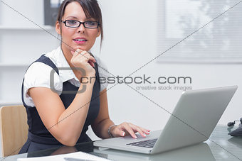 Confident female executive with laptop at desk