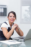 Smiling female executive sitting with laptop at desk