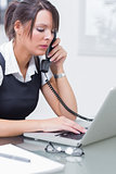 Business worker using landline and laptop