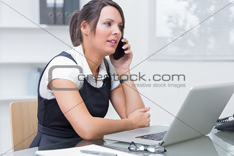Female executive on call in front of laptop at desk