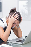 Frustrated business woman with head in hands in front of laptop
