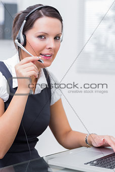 Female executive wearing headset while using laptop at desk