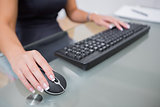Woman using computer mouse and keyboard at desk